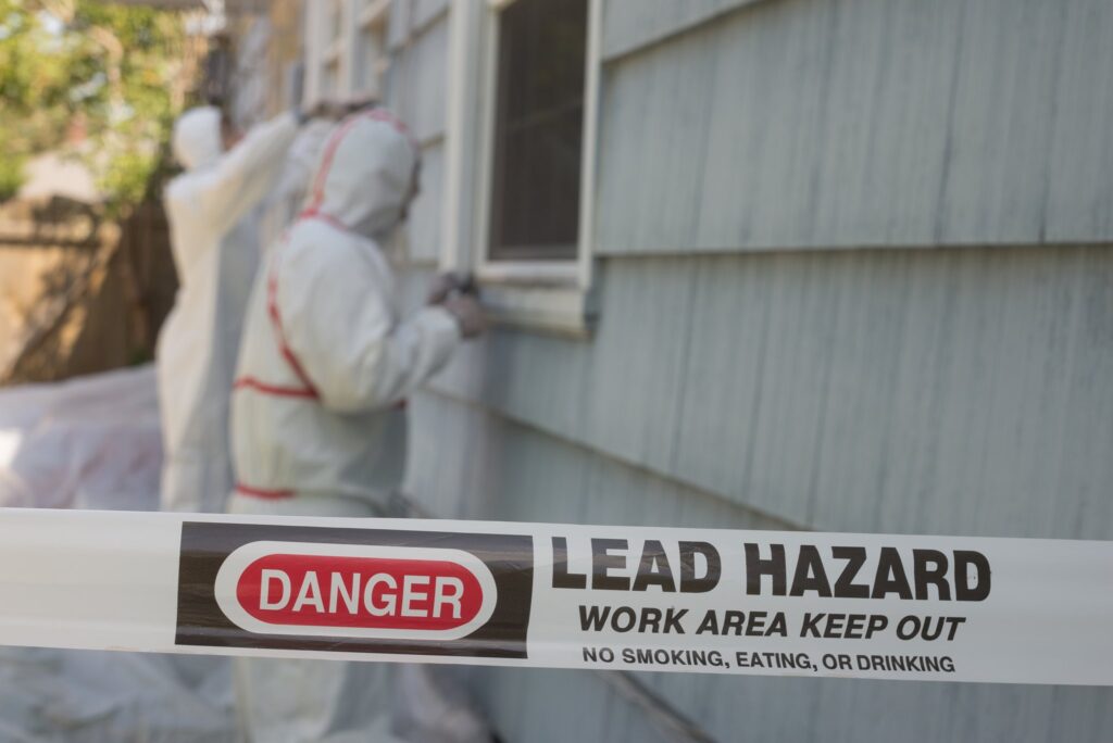 Workers in protective gear at lead hazard site.